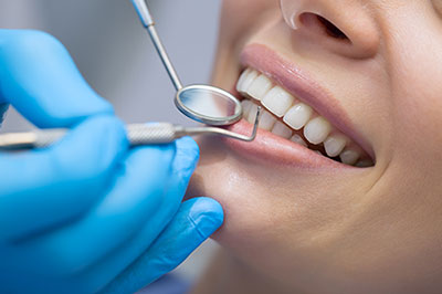 A dental professional performing a teeth cleaning procedure on a patient s mouth, with a focus on the use of dental tools and equipment.