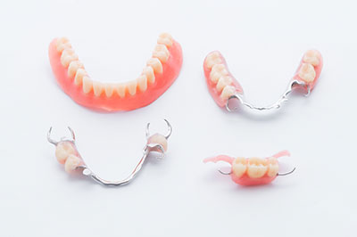 The image shows a collection of dental implants, including full sets and individual teeth, displayed against a white background.