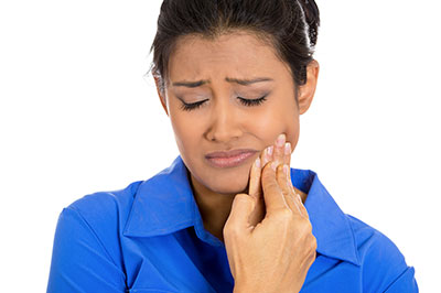 A woman with a concerned expression, looking at her hand which is touching her face, possibly scratching or rubbing it.