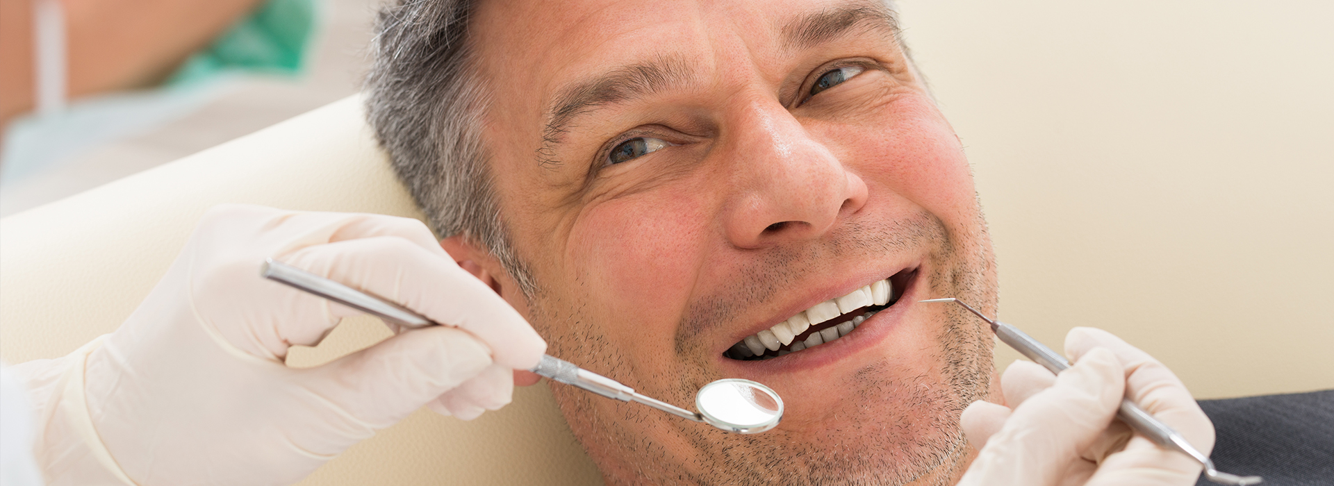 A man in a dental chair receiving dental treatment, with a smile on his face.