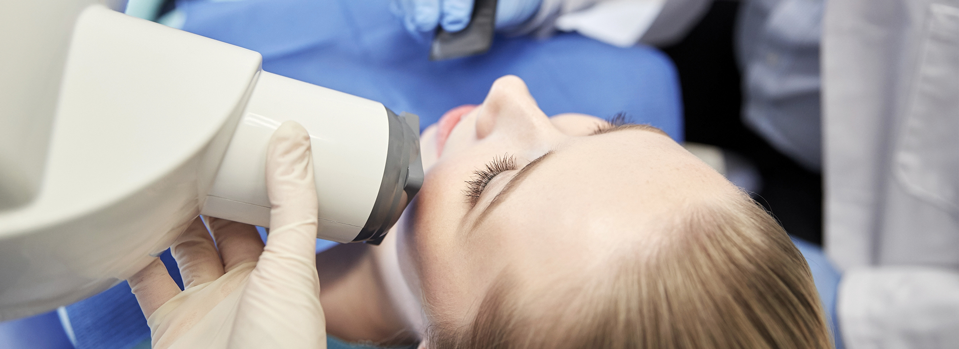 A woman receiving dental care, with a dentist using a microscope to examine her mouth.