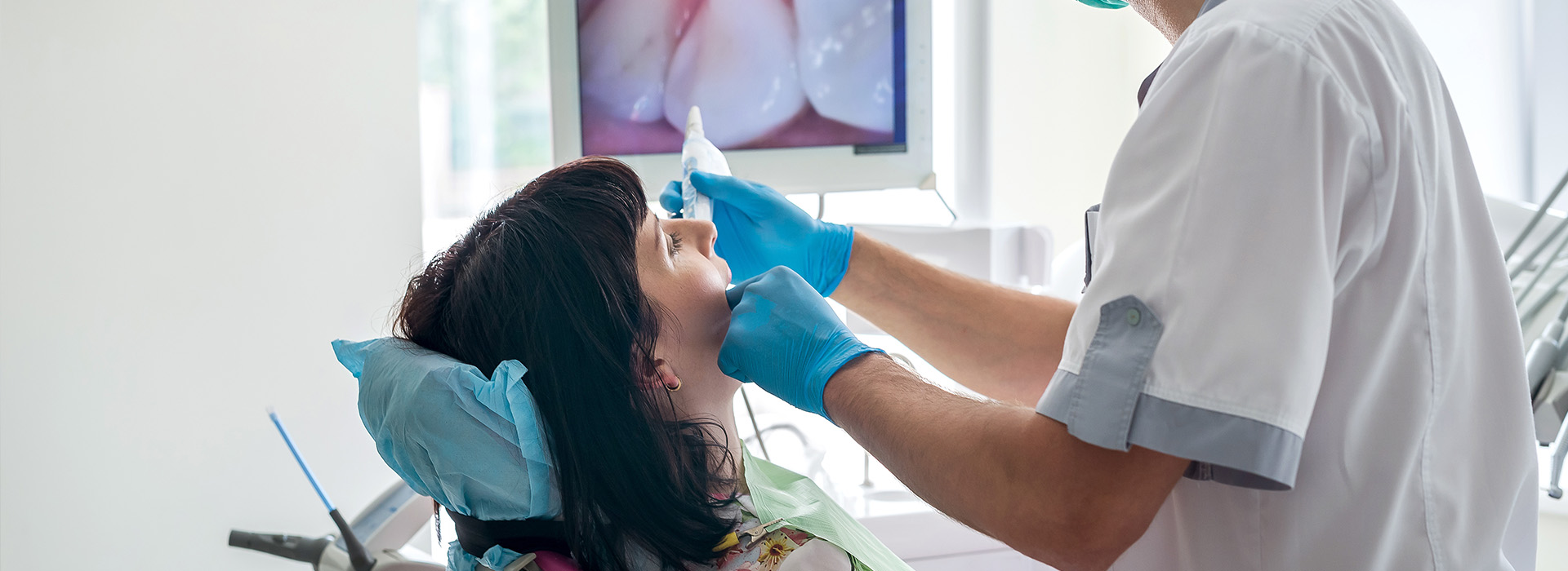 A dental professional is performing a procedure on a patient in a dental office setting.