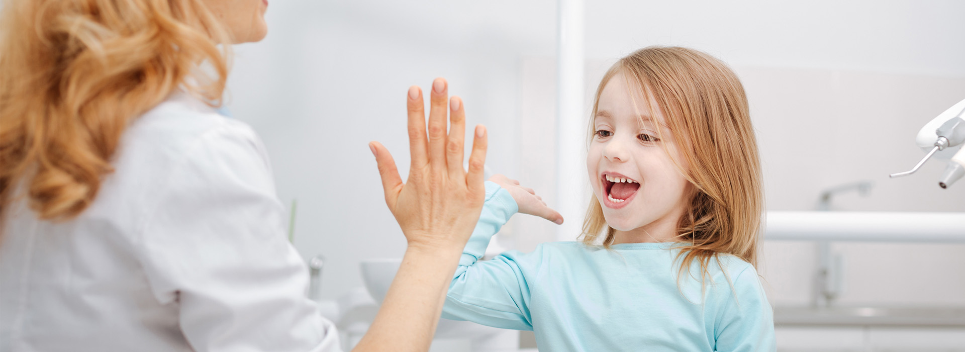 A woman and a young girl are in a bathroom, with the woman giving a thumbs-up gesture to the child.