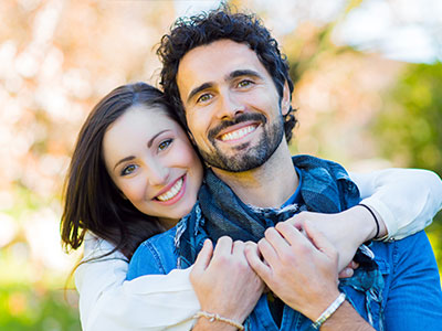 A man and a woman embracing each other, smiling and posing for the photo.