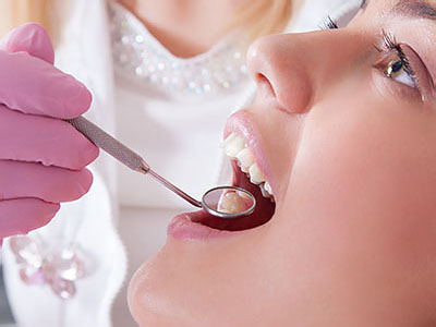 The image shows a dental professional performing oral care on a seated patient, with the dentist using a drill and wearing protective gloves.