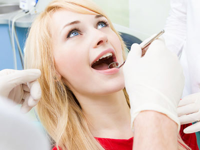 A woman receiving dental care with a smile, while a dental professional attends to her.